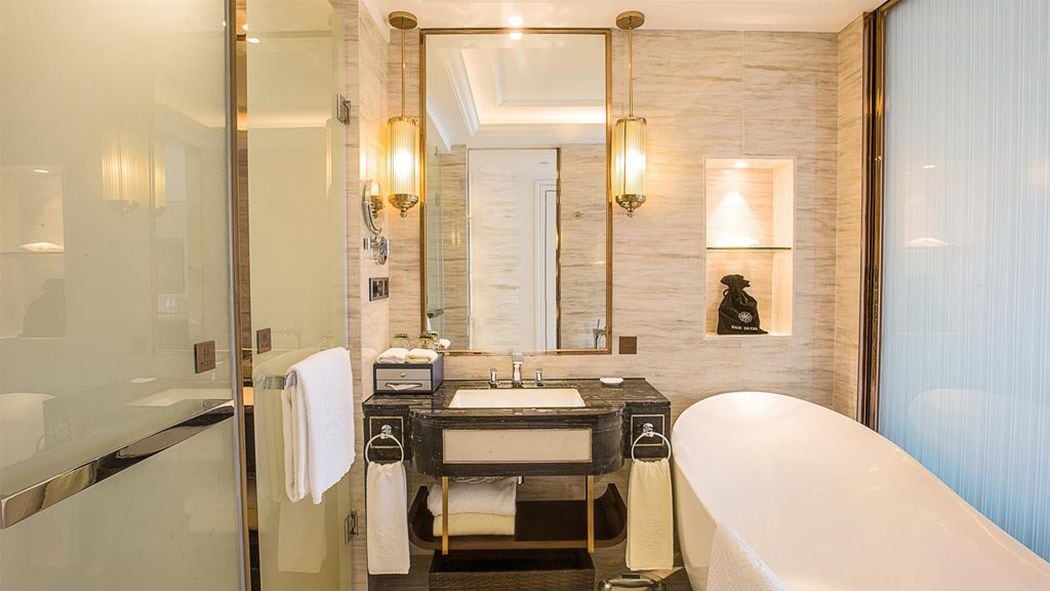 A modern bathroom with a glass shower enclosure, a freestanding bathtub, a vanity with a mirror, and a wall-mounted light fixture.