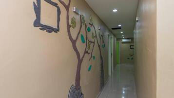 A hallway with a tree mural on the wall, a tiled floor, and recessed lighting.