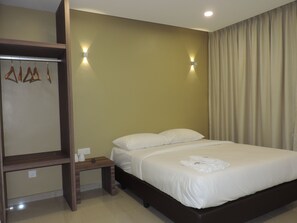 Une chambre d’hôtel comprenant un lit, une table de chevet en bois, une armoire et deux lampes fixées au mur.