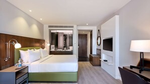 A modern hotel room with a green bed, a flat-screen TV, a desk with a lamp, and a mirror. - Country Inn & Suites by Radisson Zirakpur (Dera Bassi)