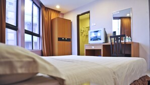 A hotel room with a bed, a desk with a computer, a chair, and a mirror.