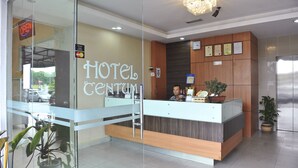 A hotel reception area with a modern design, including a reception desk, a clock, and framed certificates on the wall.
