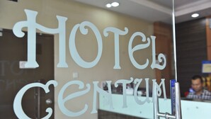 A hotel reception area with a glass door displaying the name "Hotel Centum".