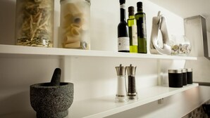 A kitchen shelf with jars of pasta, bottles of olive oil, and a mortar and pestle. - Central Suite - Simple2let Serviced Apartments (Halifax)
