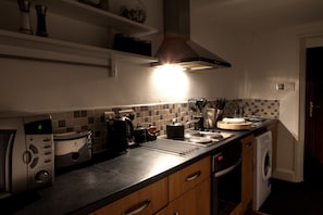 A kitchen with a toaster, kettle, sink, and a washing machine.