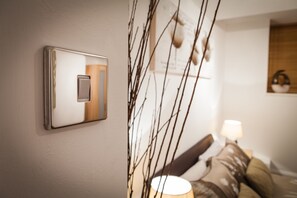 A wall-mounted light switch and a bedside lamp in a bedroom.