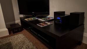 A dark wooden entertainment center with a flat-screen TV, a sound system, and magazines. - Central Suite - Simple2let Serviced Apartments (Halifax)
