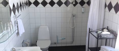 A bathroom with a white sink, toilet, and shower. There is a towel rack with folded towels.