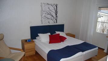Une chambre à coucher avec un lit, une chaise, une table de chevet et une fenêtre.