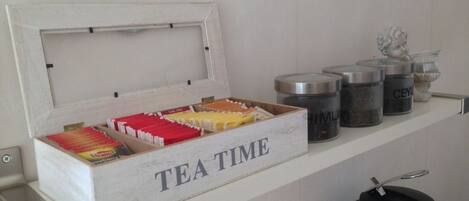A kitchen counter with a white box labeled "TEA TIME" containing tea bags and a tea kettle.