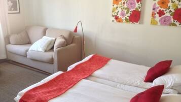 Ein Zimmer mit einem Bett, einer Couch und zwei Blumenbildern an der Wand.