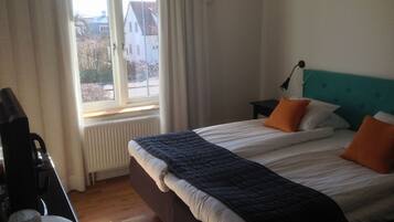 A bedroom with a bed, a nightstand, a lamp, and a view of the outside.