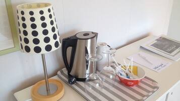 A coffee maker, a kettle, a lamp, and a tray with a cup and straws on a table.