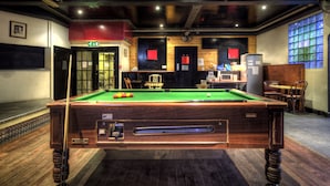 A pool table with balls, a cue stick, and a pool table with a wooden finish. - Arsenal Tavern Backpackers (London)