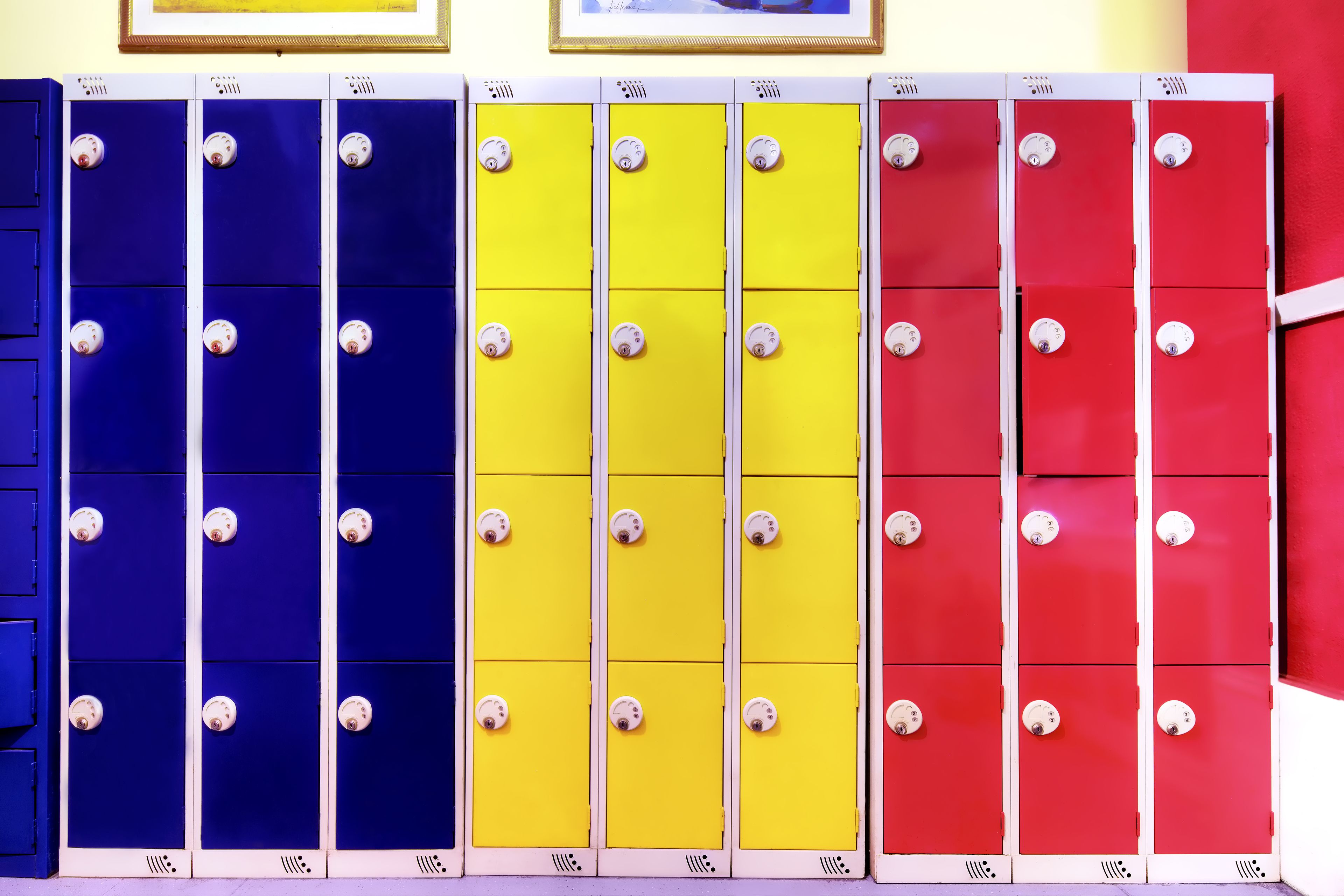 A row of lockers in blue, yellow, and red colors with white knobs.