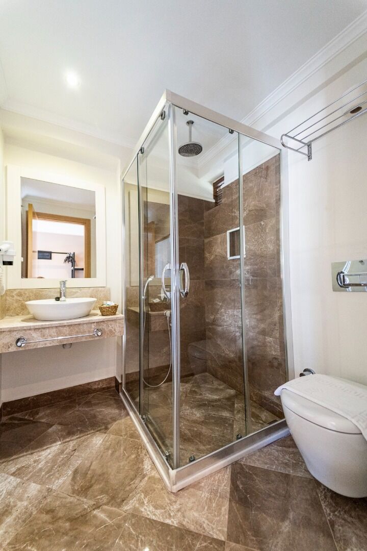 Une salle de bain moderne avec une douche à parois de verre, un lavabo blanc et des toilettes.