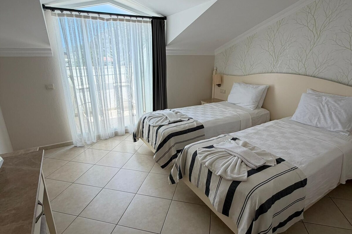 Una habitación de hotel con dos camas, un tragaluz y vistas al exterior.