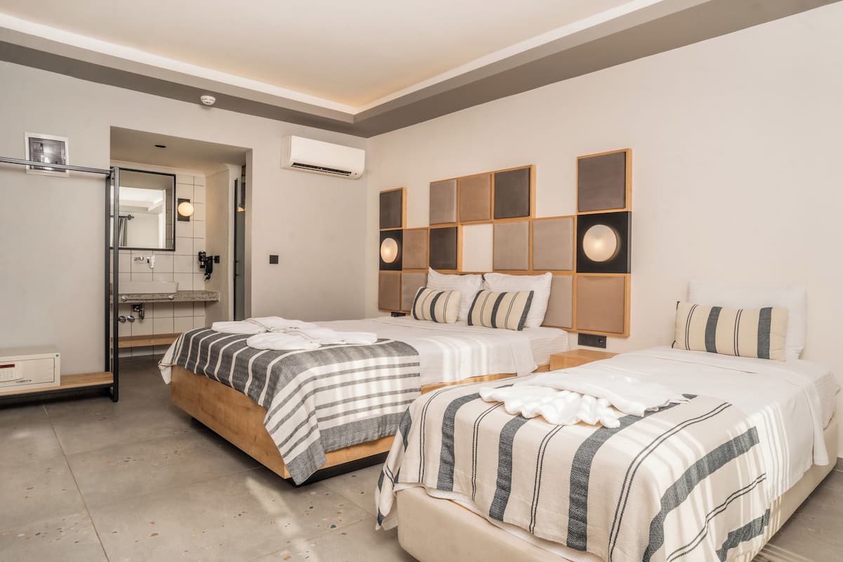 A hotel room with two beds, a bathroom with a mirror, and an air conditioning unit.