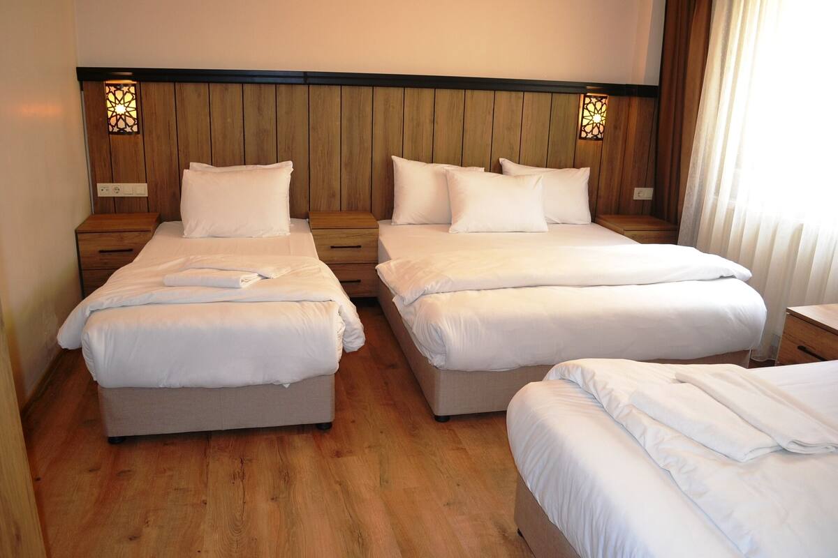 A hotel room with two beds, wooden headboards, and bedside lamps.