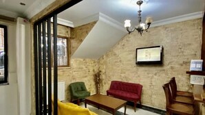 A room with a high ceiling, exposed brick walls, a chandelier, a red sofa, a yellow armchair, and a wooden table. - Istanbul Comfort Hotel (Istanbul)