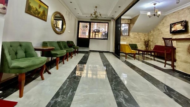 A hotel lobby with a marble floor, green and yellow chairs, a wooden reception desk, and a large mirror on the wall. - Istanbul Comfort Hotel (Istanbul)