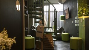 Un intérieur moderne avec un escalier en colimaçon, des sièges verts et le logo de Mossmania bien visible.