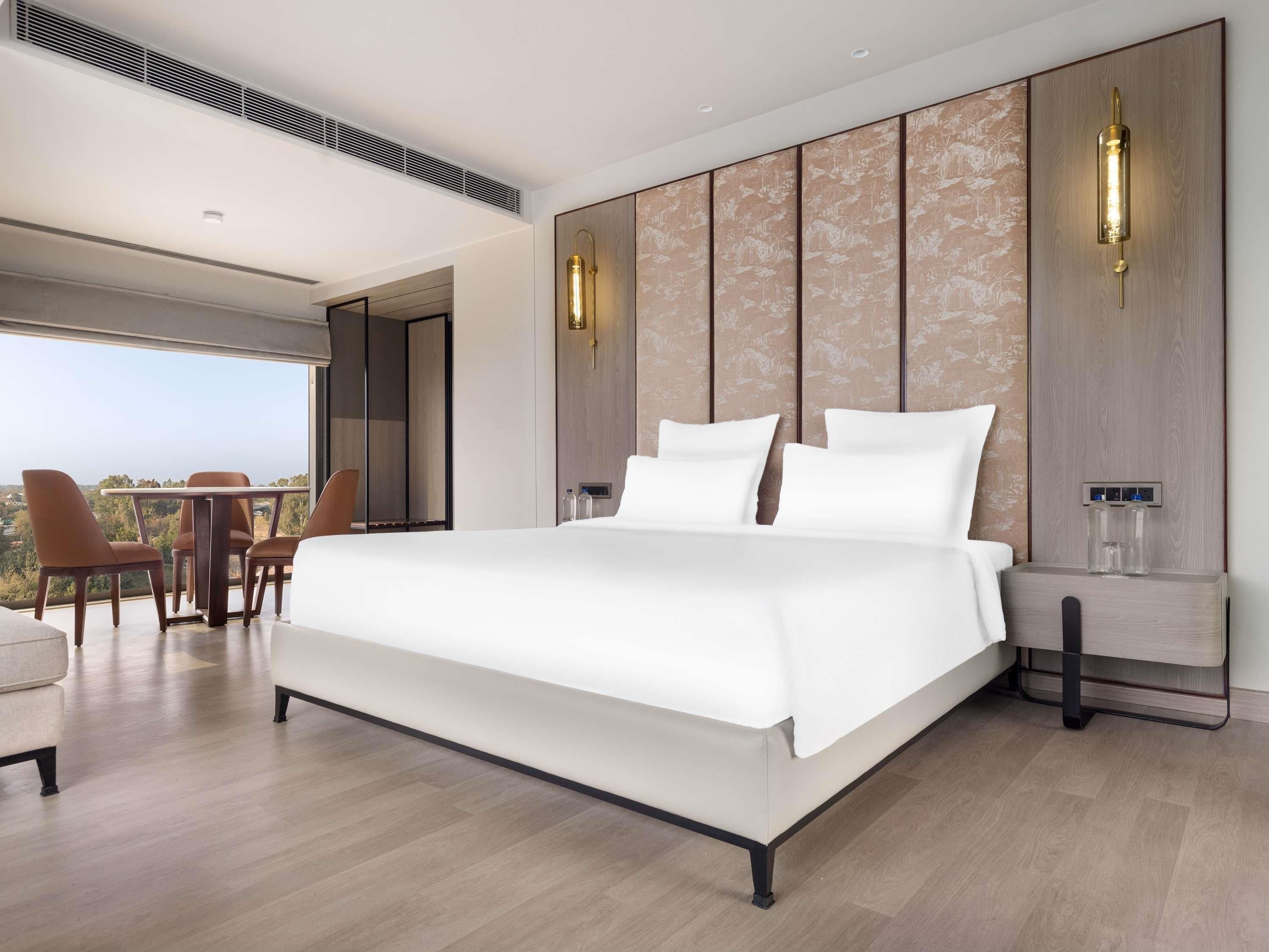 Un dormitorio moderno con una cama grande, una zona de comedor con sillas y vistas al exterior.