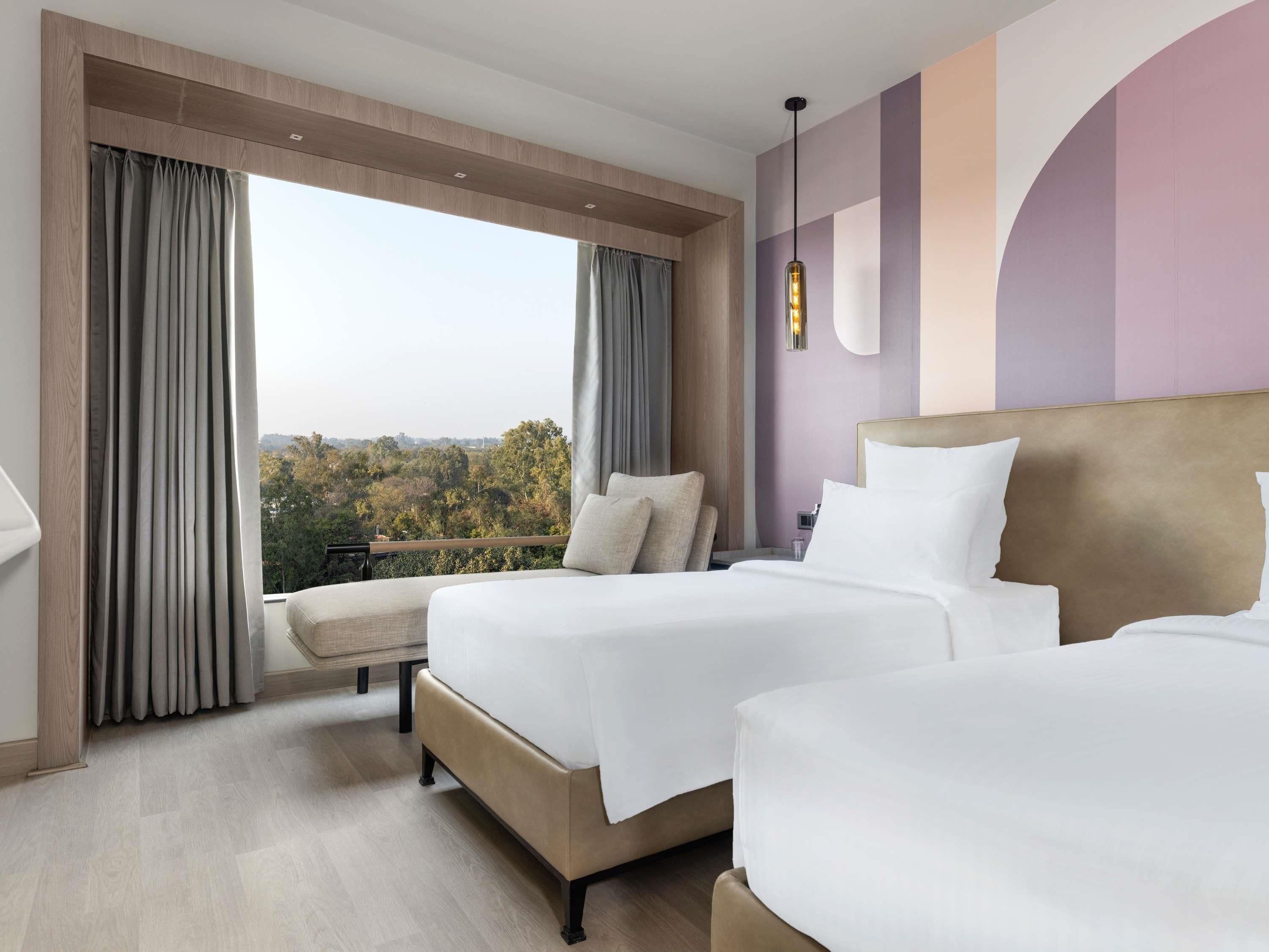 A hotel room with two beds, a view of the outdoors, and a modern design.