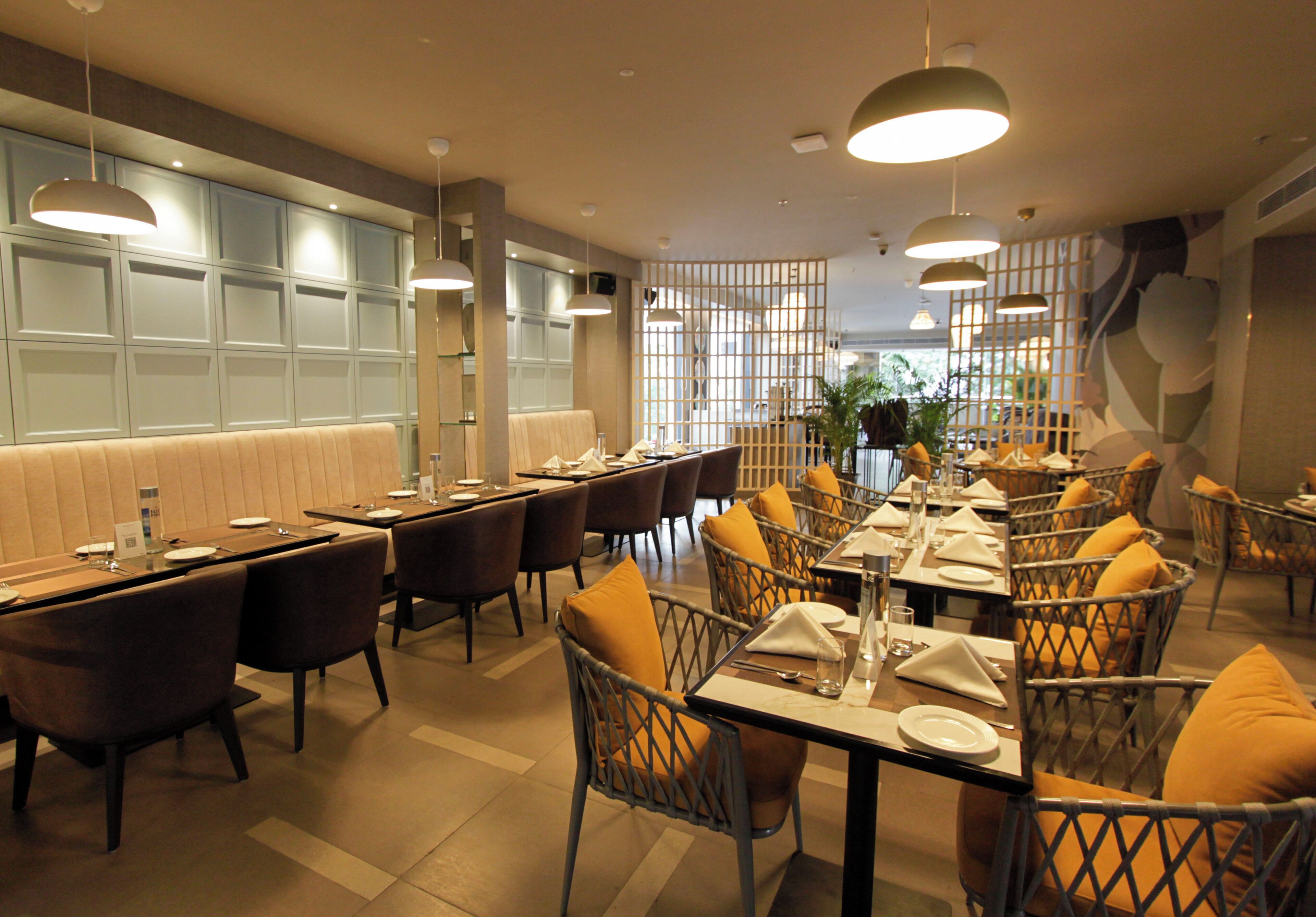 A restaurant with multiple tables and chairs, a bar area, and a view of the outdoors.