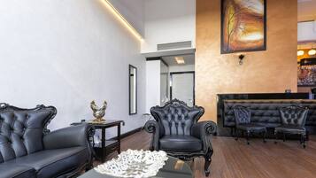 A spacious lobby with a black leather sofa, a tufted armchair, and a seating area with black leather chairs.