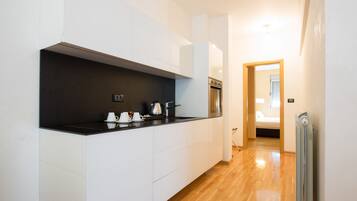 Una cocina moderna con armarios blancos, encimera negra y suelo de madera.