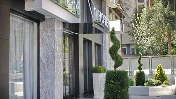 A modern hotel entrance with a marble facade, large windows, and a sign indicating the hotel's name.