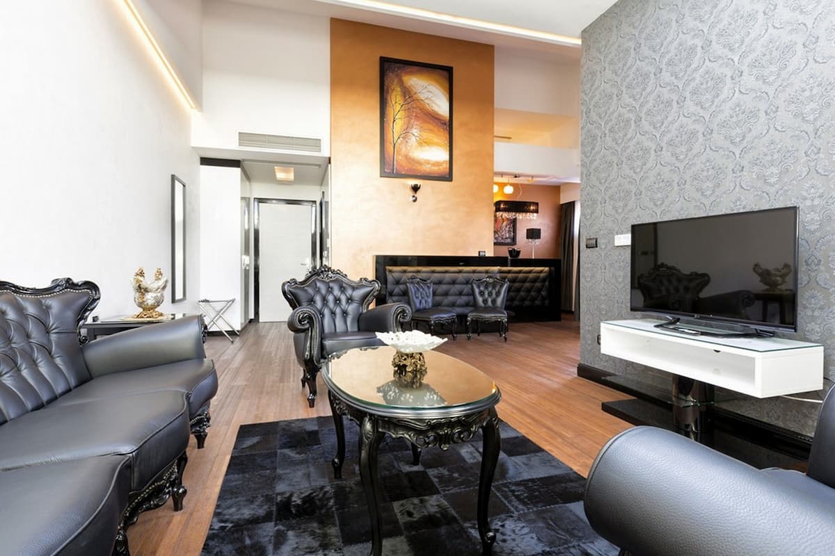 Uma sala de estar moderna com sofá, poltronas, mesa de centro de vidro e televisão de tela plana.