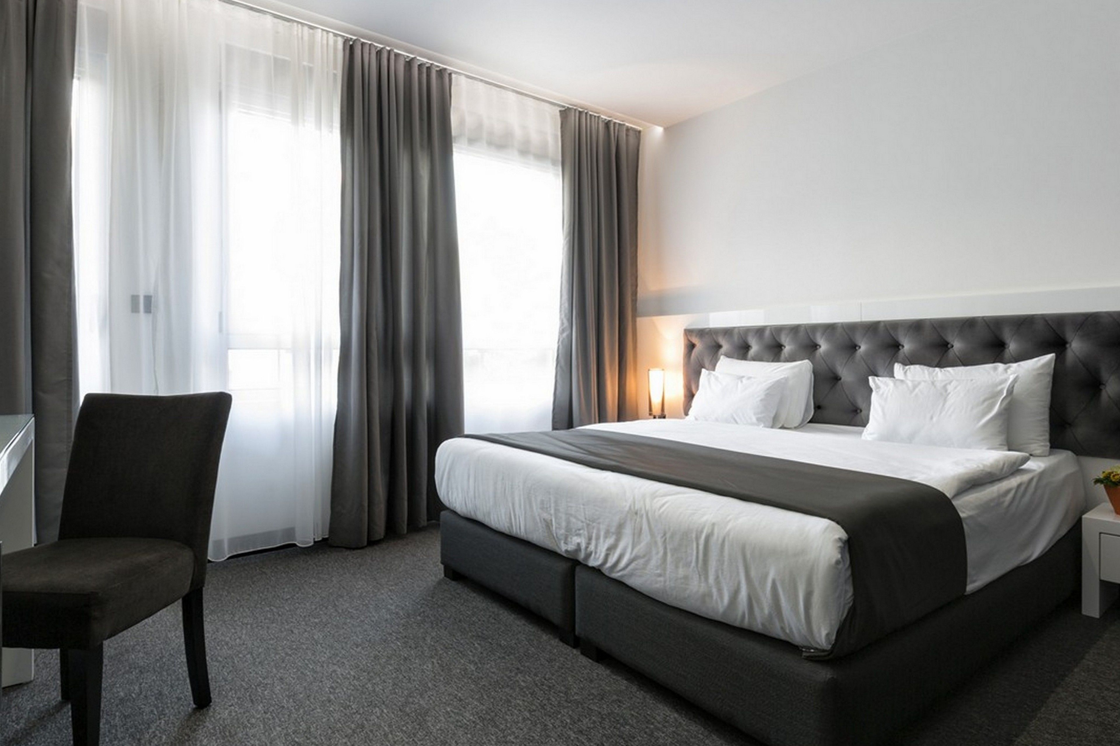 Ein Hotelzimmer mit einem großen Bett, einem Sessel, einem Schreibtisch und einer Lampe.