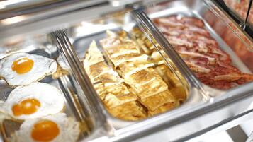 A breakfast buffet with fried eggs, omelets, and bacon.