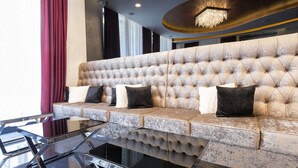 Un sofá lujoso con diseño capitonado, situado en un interior moderno con una mesa de vidrio al frente.