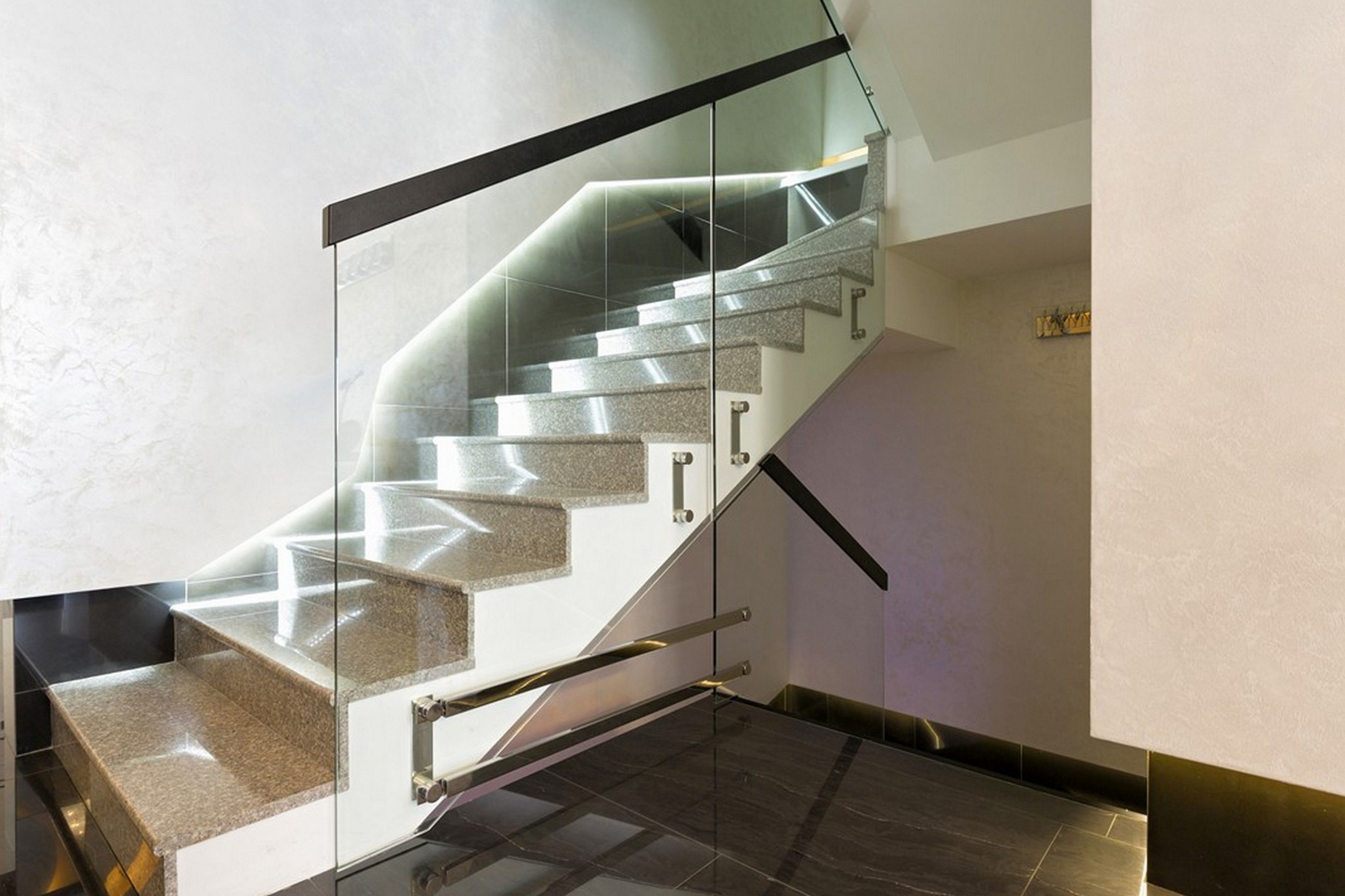A modern staircase with glass railings and granite steps.