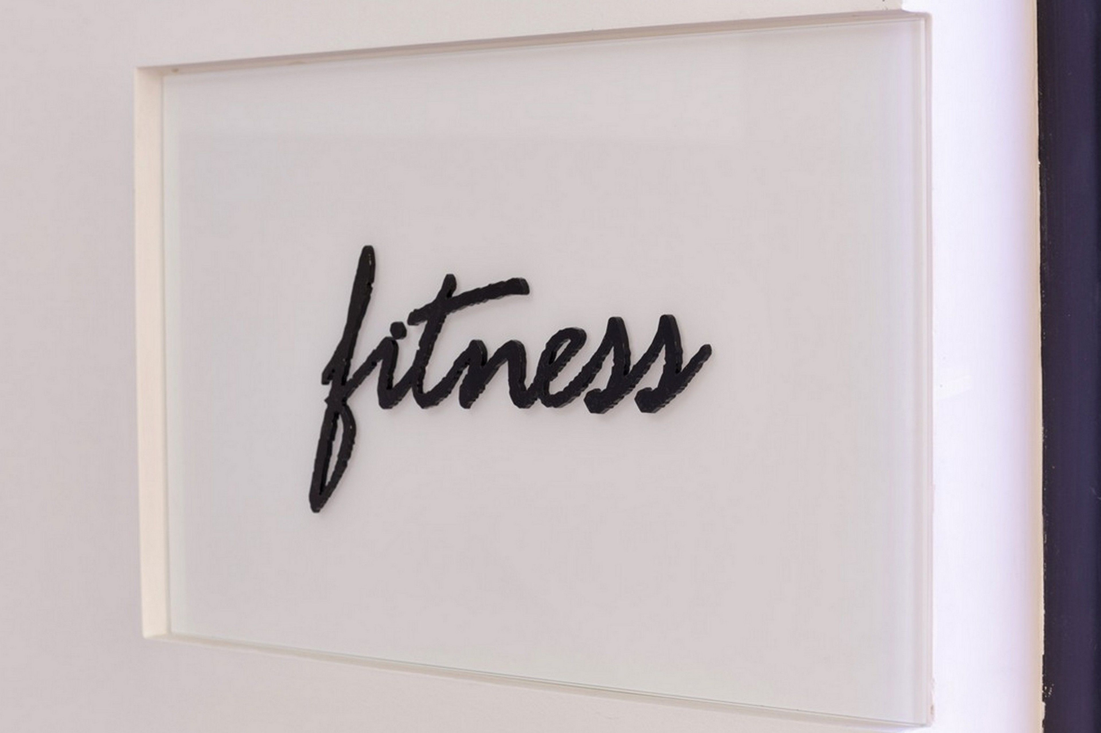 A framed sign with the word "fitness" in cursive on a white background.