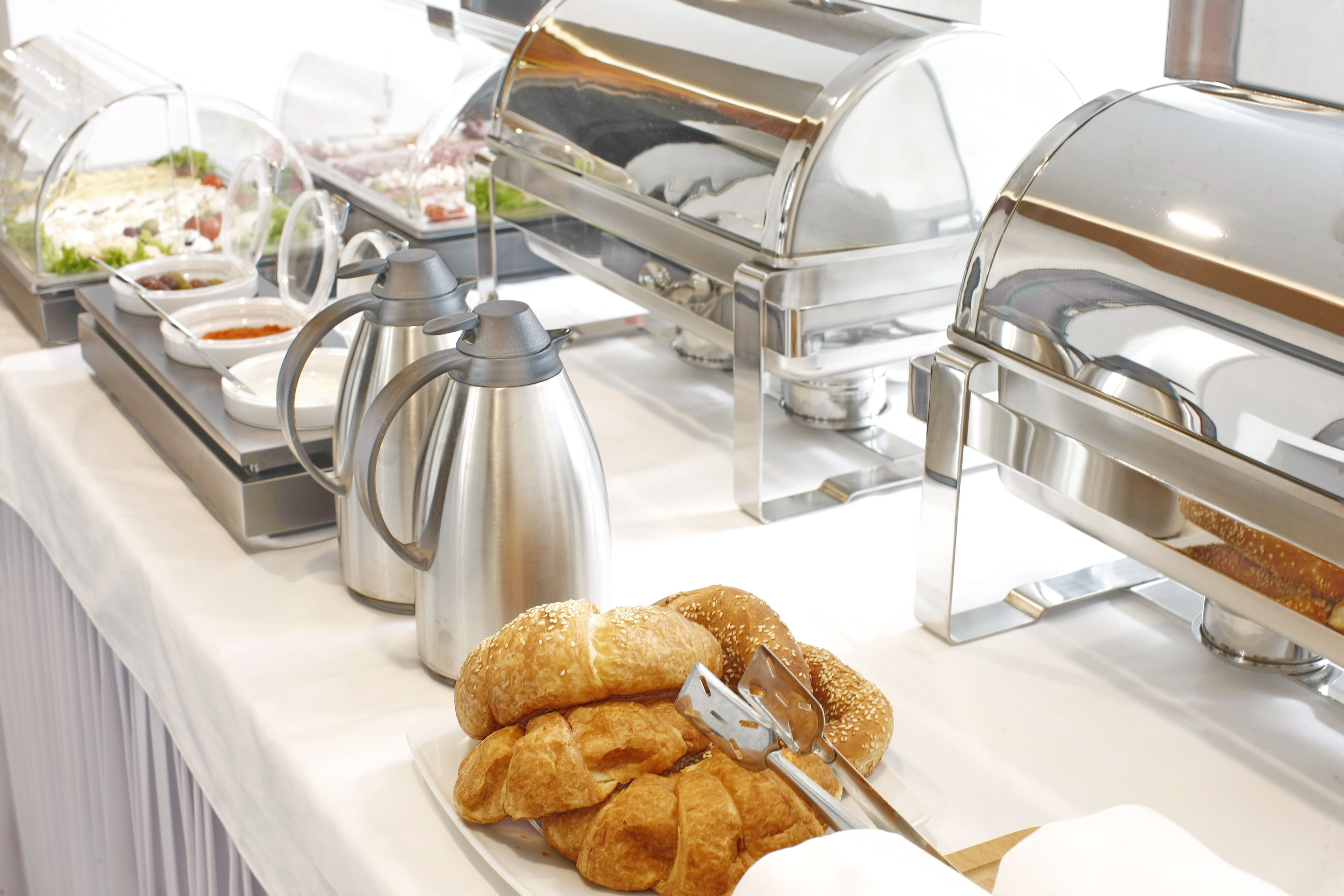 Montaje de bufé con diversos alimentos, incluyendo una estación de bebidas calientes y una selección de pasteles.