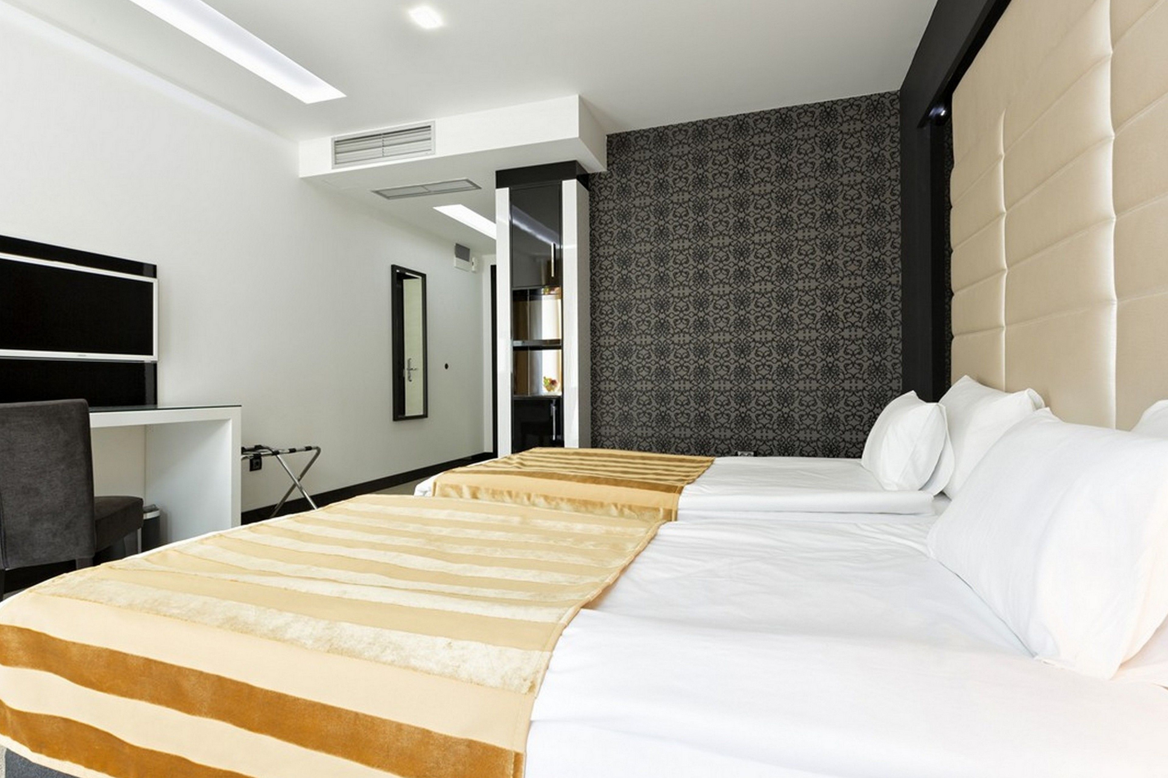 Una habitación de hotel con dos camas, un escritorio, una silla y un armario.