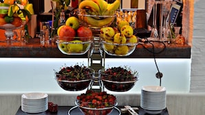 A buffet setup with various fruits and a cross on the table.
