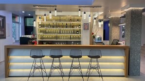A modern bar area with a counter, bar stools, and shelves of liquor bottles.