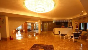 Eine großzügige Lobby mit Marmorboden, einer Rezeption und einer Kristallleuchter.