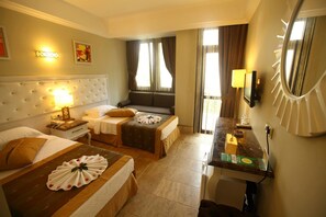 A hotel room with two beds, a small desk, a mirror, and a window with curtains.