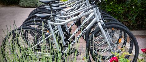 Várias bicicletas estacionadas em um jardim com vegetação e flores.