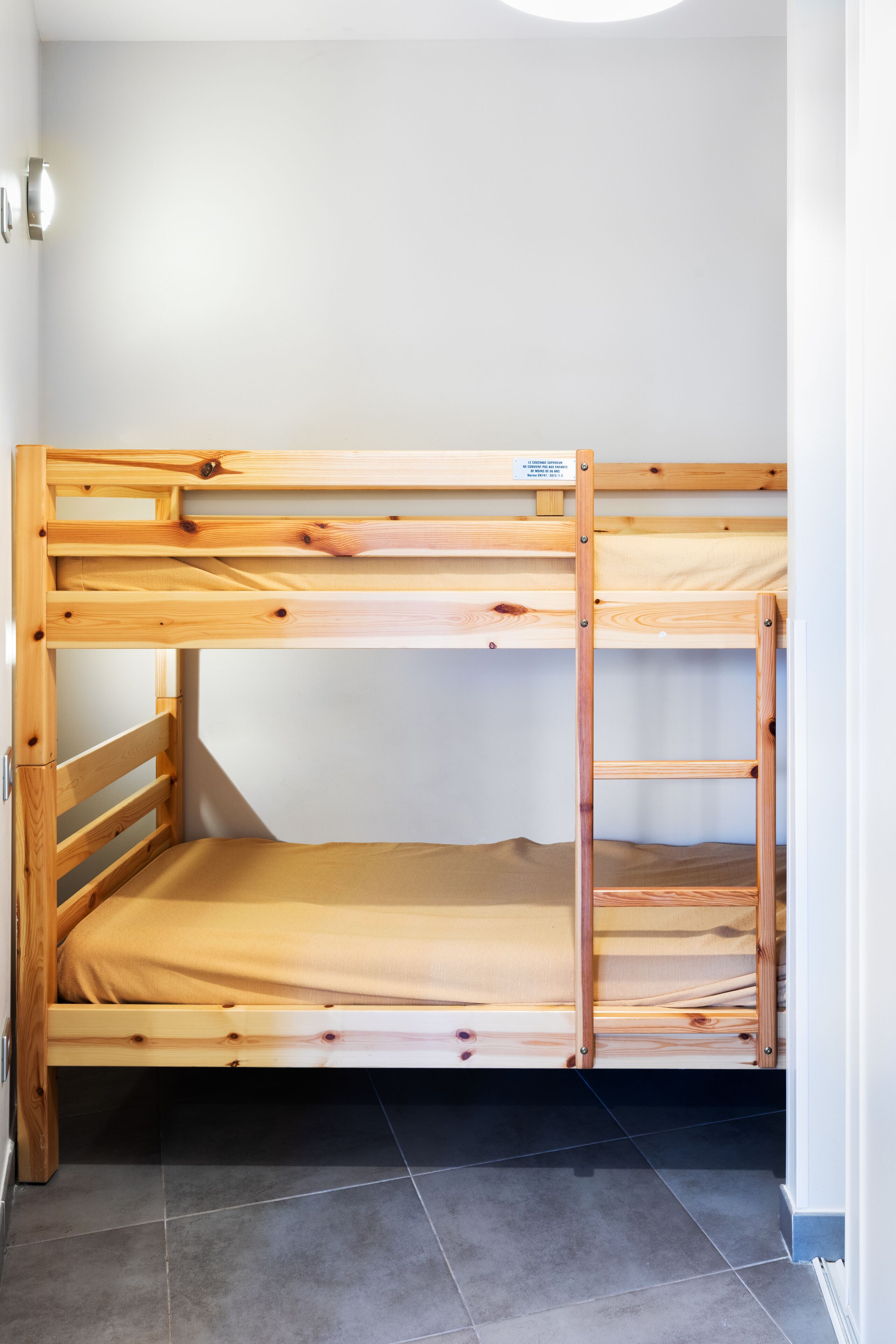 Un lit superposé avec une structure en bois et un matelas.