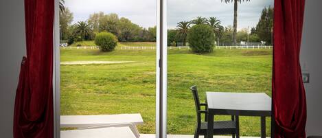 A room with a sliding glass door leading to a grassy outdoor area with a white table and chair.