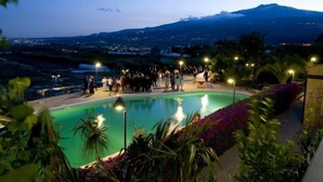 A pool area with a mountain view, surrounded by greenery and outdoor lighting. - Serra San Biagio (Calatabiano)