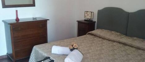Un dormitorio con una cama, un aparador de madera, una mesita de noche y una silla.