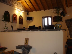 A cozy living room with a stone fireplace, wooden ceiling beams, a television, and various decorative items.